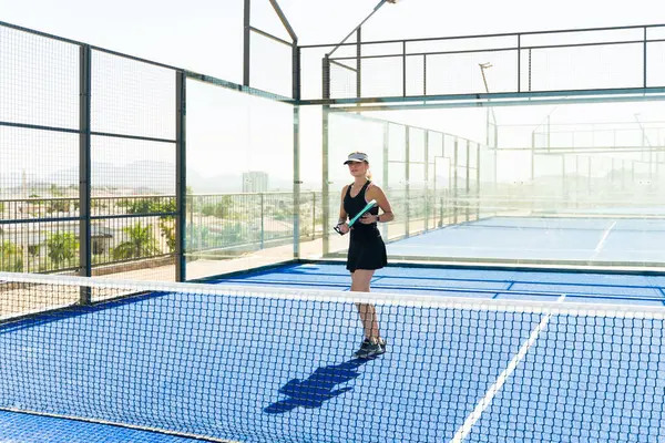 Çekici beyaz kadın dışarıda antrenman yapıyor ve egsersiz yaparken padel tenis oynuyor.