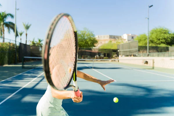 Close up of a woman holding a tennis racket and a tennis ball on the outdoor court while ready for a tennis game