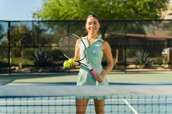 Smiling beautiful mexican woman and tennis player looking happy while practicing tennis sports