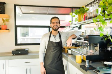 Neşeli İspanyol genç adam kahveci olarak çalışıyor ve kahvecide çalışırken gülümsüyor.