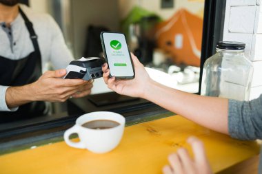 Kahve alırken akıllı telefon uygulaması ile ödeme yapan bir bayan müşterinin fotoğrafını çek.