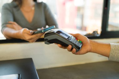 Kadın müşteri kahve siparişini akıllı telefonuyla ödüyor. Temassız ödemeyle kafeden yemek alıyor.