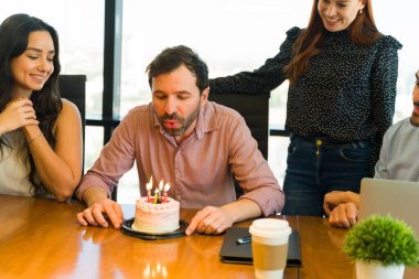 Heyecanlı bir grup ofis çalışanı toplantı odasında doğum gününü kutluyor ve tezahürat yapıyor.