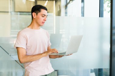 Ofiste dizüstü bilgisayar üzerinde çalışan beyaz bir adamın profil görüntüsü.