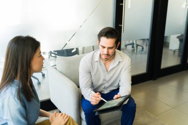 Kafkasyalı işadamı elinde bir tablet ile bir müşteriyle dijital kontratı inceliyor.