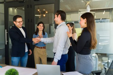 Heyecanlı iş adamları el sıkışıyor ve bir iş anlaşmasının kapanışını kutluyor.