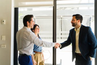 Takım elbiseli bir İspanyol işadamının portresi toplantı odasında iki iş adamıyla el sıkışıyor.