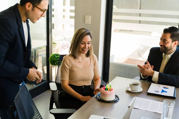 Group of office workers celebrating a woman\'s birthday with some cake