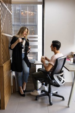 Bir kadının kahve koyduğu ve iş arkadaşıyla kahve molası verdiği geniş bir manzara.