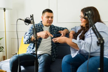 Podcast yardımcı sunucuları akıllı telefondan kısa mesajlar okuyorlar ve bir bölümü kaydederken sosyal medya hakkında konuşuyorlar