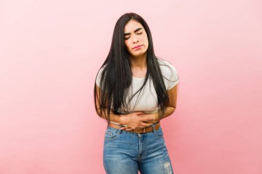 Kötü dönemden muzdarip üzgün İspanyol kadın karnına dokunurken kramp ya da karın ağrısı çekiyor.