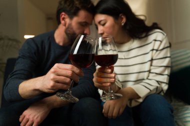 Evde bir randevu gecesi şarap içerken öpüşmek üzere olan romantik evli bir çift. 