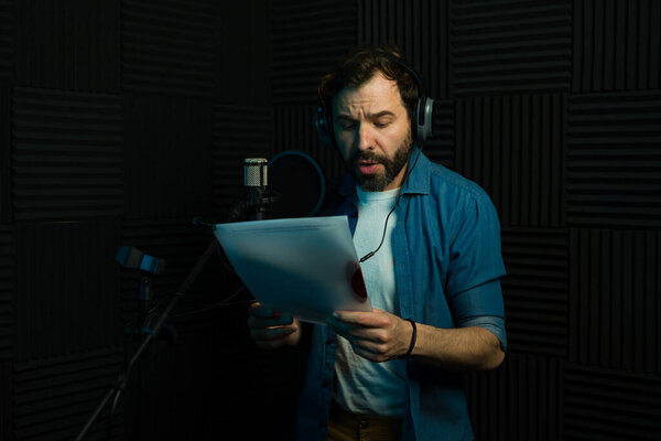 Focused male voice actor performs script reading into a microphone in a professional studio