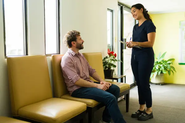 Fröhliche Krankenschwester Gespräch Mit Einem Männlichen Patienten Wartezimmer Der Vor lizenzfreie Stockbilder