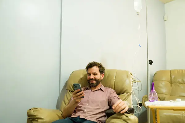 Aufgeregter Mann Der Klinik Lächelt Während Therapie Und Vitamincocktail Bekommt lizenzfreie Stockbilder