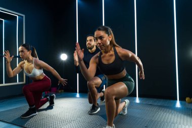 Dinamik grup modern bir fitness stüdyosunda egzersiz yapıyor.