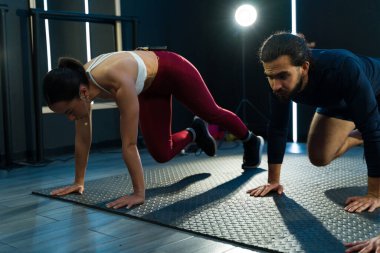 İki kişi bir spor salonunda dağcılık yapıyor. Güç ve konsantrasyon gösterisi yapıyorlar.
