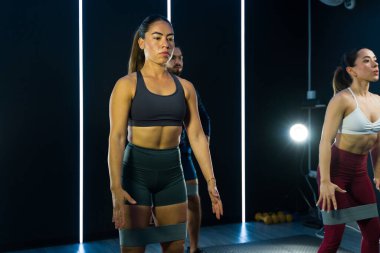 Dayanıklılık eğitimi için direnç bantlarıyla egzersiz yapan fitness sınıfındaki odaklanmış bireyler