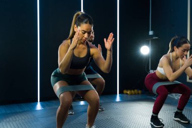 Üç Latin, modern bir spor salonundaki direniş bantlarını kullanarak zorlu bir antrenmana giriştiler.