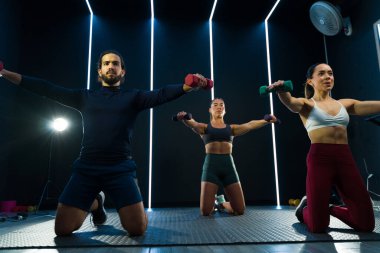 Çağdaş bir spor salonunda ağırlıklarla fitness kursuna katılan çeşitli gruplar