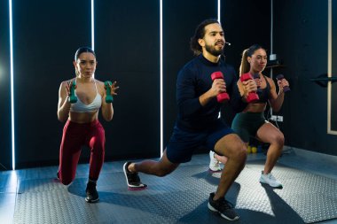 Dinamik fitness eğitmeni motivasyonlu katılımcılarla yüksek yoğunluklu bir çalışma yürütüyor.