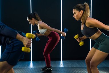 Modern bir spor salonunda ağırlık kaldıran katılımcılarla enerji antrenmanı.