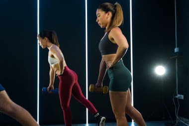 Aktif insanlar, modern bir spor salonunda ağırlık çalışması yapıyorlar.