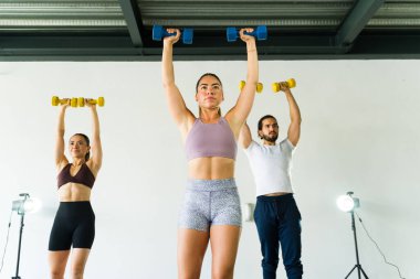 Spor salonunda dambılları kaldıran üç kişi antrenmanlarına odaklanmıştı.