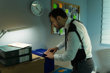 Deneyimli araştırmacı, iyi organize edilmiş, parlak bir ofis ortamındaki ipuçlarını dikkatlice analiz eder.