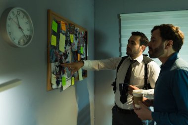 İki dedektif bir davada birlikte çalışıyor, geceleri bir tahtada kanıtları analiz ediyor ve biraz kahve içiyor.