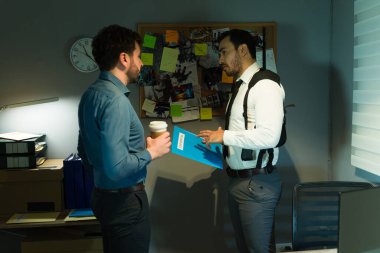 Iki müfettiş delil uzerinde isbirligi yapar ve belli belirsiz bir ofiste bir dava hakkinda strateji belirler.