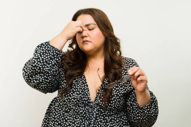 Stresli şişman kadın burnunun köprüsüne dokunuyor ve stüdyoda gözlük takmaktan bıkıyor.