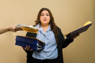 Stüdyo ortamında çalışmaktan bunalmışken daha çok evrak işi verdiği için büyük boy kadın profesyonel stresli görünüyor.