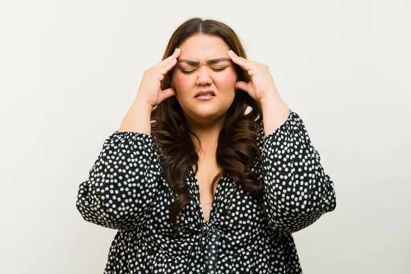 不安なプラスサイズの女性は頭を締め付け 頭痛や片頭痛の症状を示しています ストックフォト