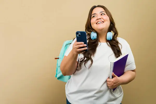 Boa Aparência Hispânica Size Mulher Segurando Material Escolar Usando Smartphone Fotos De Bancos De Imagens