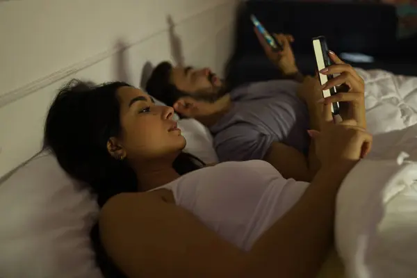 Casal Jovem Deitado Cama Noite Absorvido Individualmente Suas Telas Smartphones — Fotografia de Stock