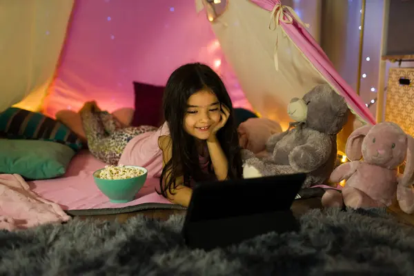 Wesoła Dziewczynka Cieszy Się Nocą Filmową Domowym Namiocie Otoczona Pluszowymi — Zdjęcie stockowe
