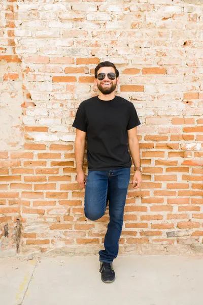 Szczęśliwy Hiszpan Czarnej Koszulce Dżinsach Pozujący Makiety Rustykalnym Murowanym Tłem Obraz Stockowy
