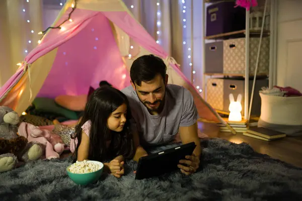 父と娘は映画を見て一緒にポップコーンを食べながら屋内で暖かい夜を共有しています ストック写真