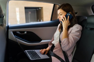 Profesyonel iş kadını dizüstü bilgisayarı ve akıllı telefonu ile iş yerine gidip gelirken, verimliliği ve verimliliği somutlaştırıyor.