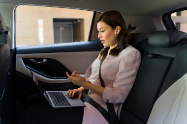 Modern iş hareketliliği, profesyonel bir kadının otomobille seyahat ederken laptopuyla görüntülü konuşma yapmasıyla sembolize ediliyor.