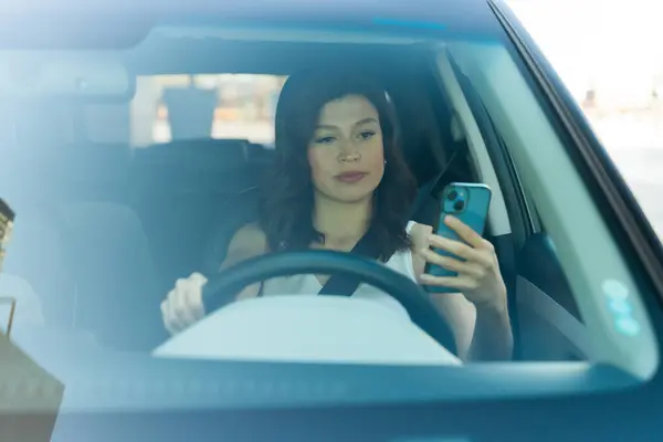 Pretty Woman Safely Checking Her Phone While Driving Her Car รูปภาพสต็อก