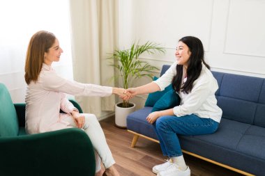 Professional female psychologist welcoming patient with a handshake before a therapeutic session, symbolizing trust and mental health support