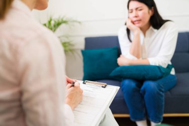 Focused female psychologist attentively listens to a distressed woman sharing her problems during a therapy appointment for mental health