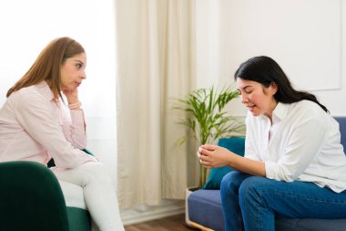 Focused psychologist attentively listens to a distraught woman sharing her problems during a mental health therapy session in a calm setting