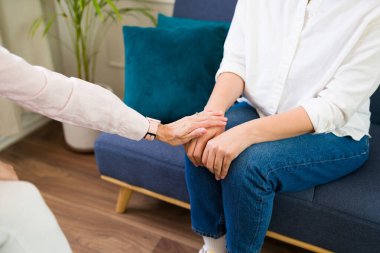 Closeup of a woman psychologist offering reassurance and comfort to a patient during a mental health therapy session by touching her hand