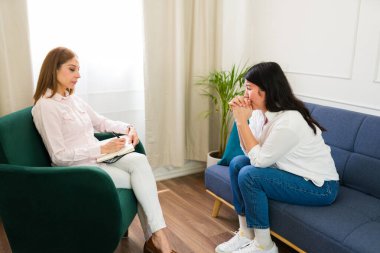 Professional psychologist attentively listens to a distressed woman during a therapy session, promoting mental health and emotional understanding