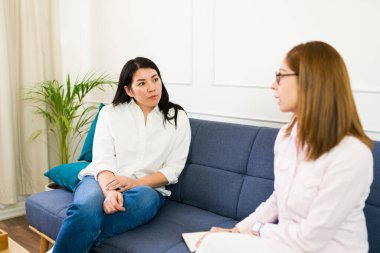 Caucasian woman paying attention to her psychologist as she shares some insights during a therapy session