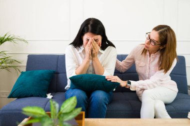 Female psychologist provides support to a tearful client in a one-on-one therapy session, capturing a genuine display of mental health support