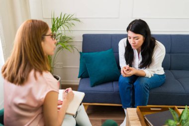 Female therapist listens carefully to a young woman during a counseling session, dedicated to her mental health and overall wellness